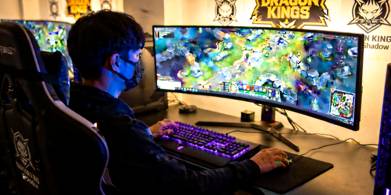 Dragon Kings战队新援Shadow在训练室专注操作键盘，背后屏幕显示游戏地图